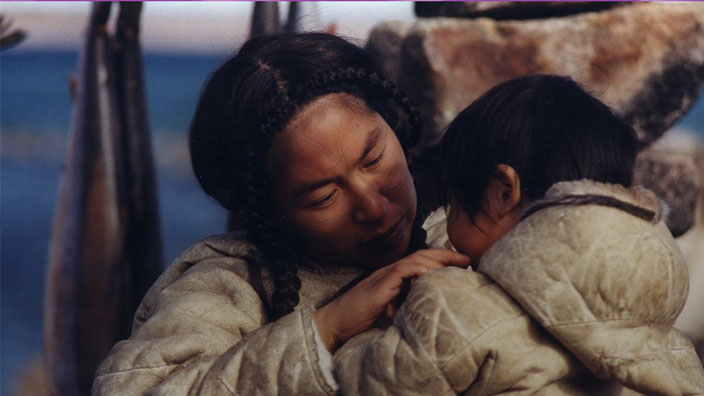 Photo of a woman holding a child, both wearing coats. 