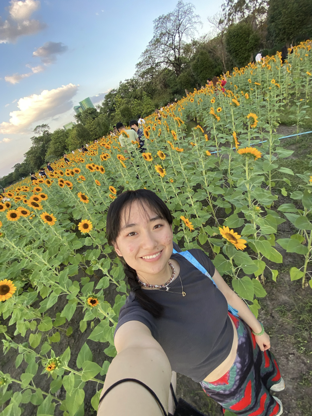 Portrait of Selina Wu smiling in a field of sunflowers.