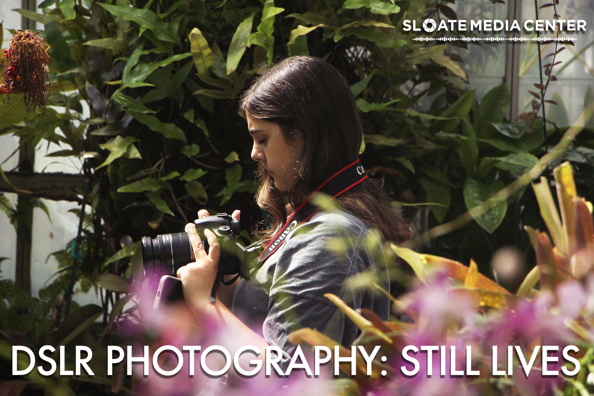 A young woman holding a dslr camera while surrounded by flowers