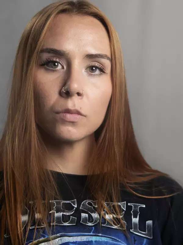 Headshot of a white woman with red-brown hair and green eyes. 