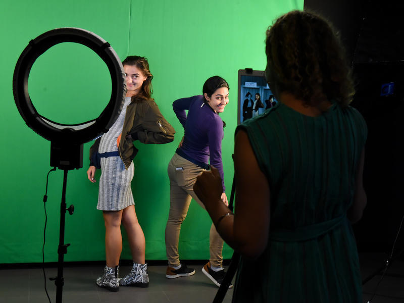 2 young women posing in front of a green screen
